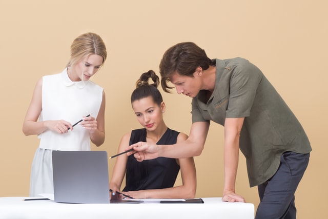 Three people acting like there is something on the laptop screen. Terrible acting.